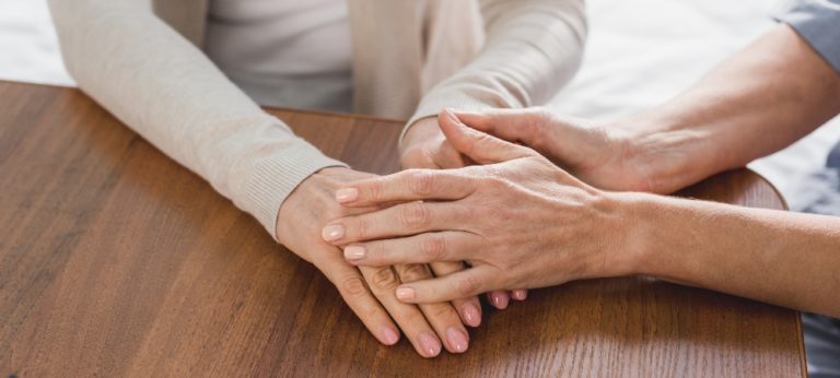 Two people holding hands over a table