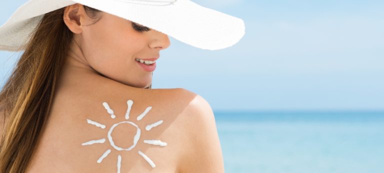 Young Woman Looking At Sun Drawn On Her Back With Suntan Lotion