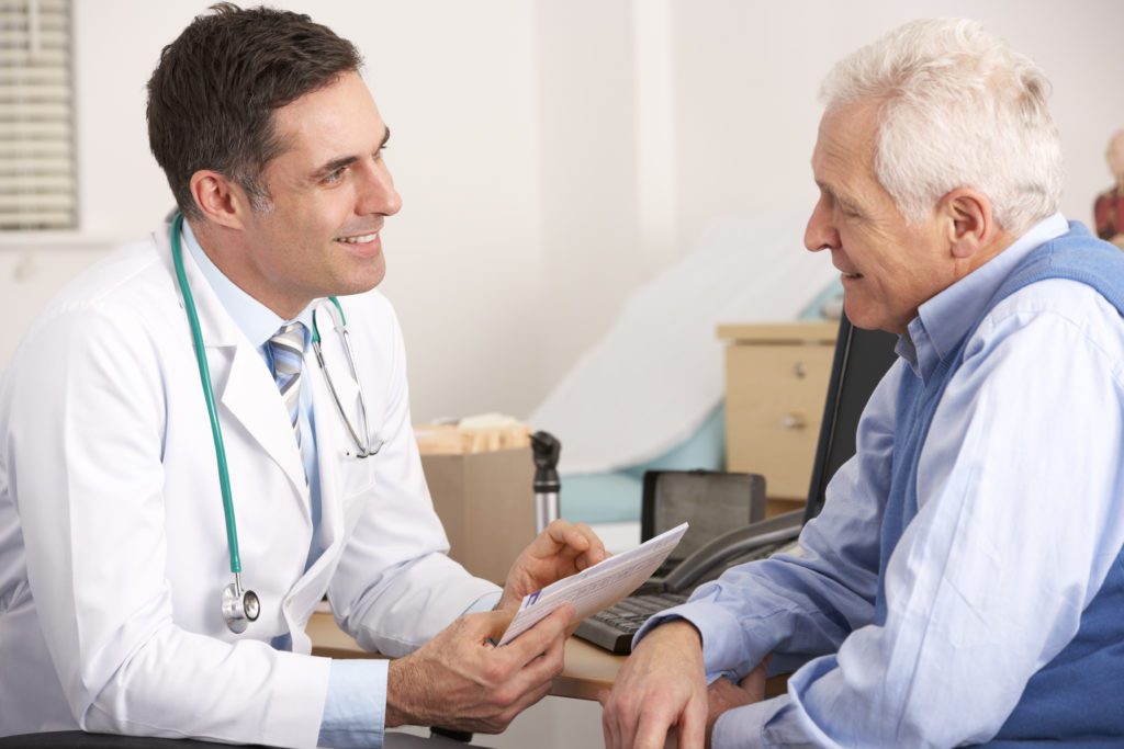 American doctor talking to senior man in surgery