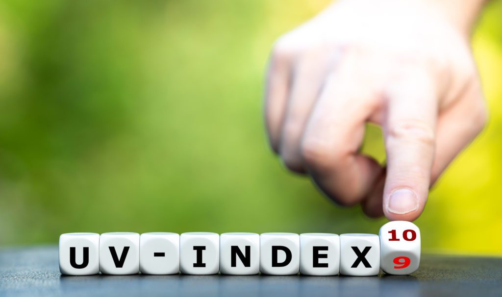 Hand turns dice and changes the expression 'uv-index 9' to 'uv-index 10'.