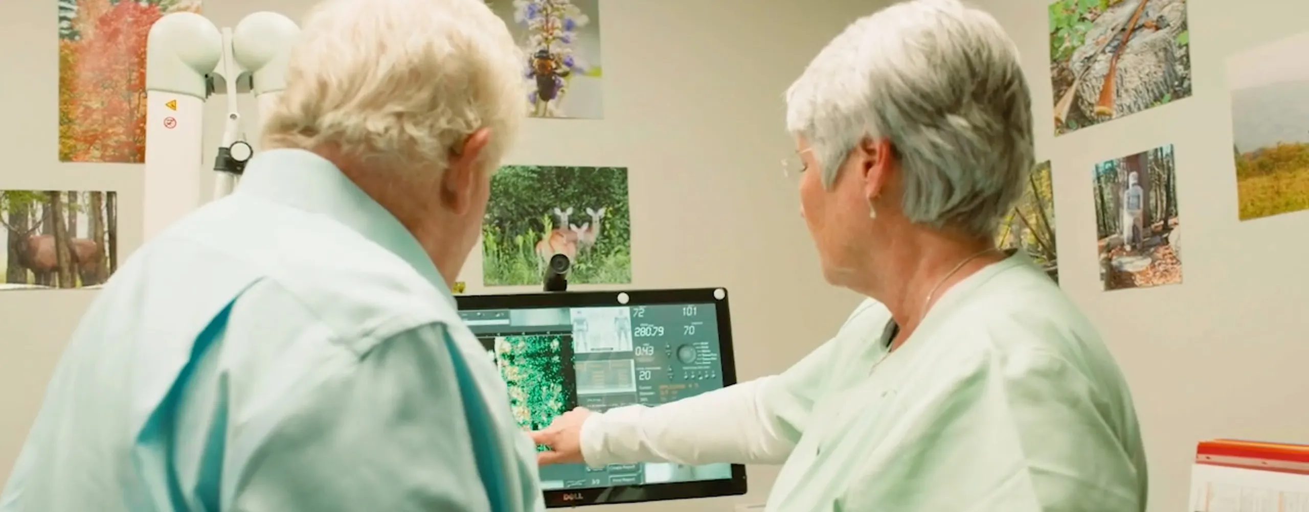 A woman and a mail doctor looking and pointing at a screen of a medical equipment