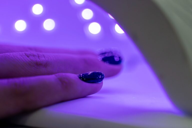 Hand under a UV nail lamp with purple light, illustrating indoor UV exposure from nail curing devices