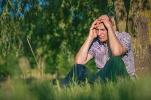 Older man sitting outdoors in bright sunlight, illustrating increased sun sensitivity and higher UV risk while on certain medications