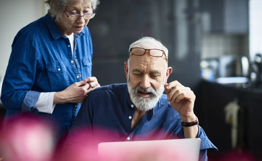 Older couple looking at a laptop together while discussing next steps for a skin concern.