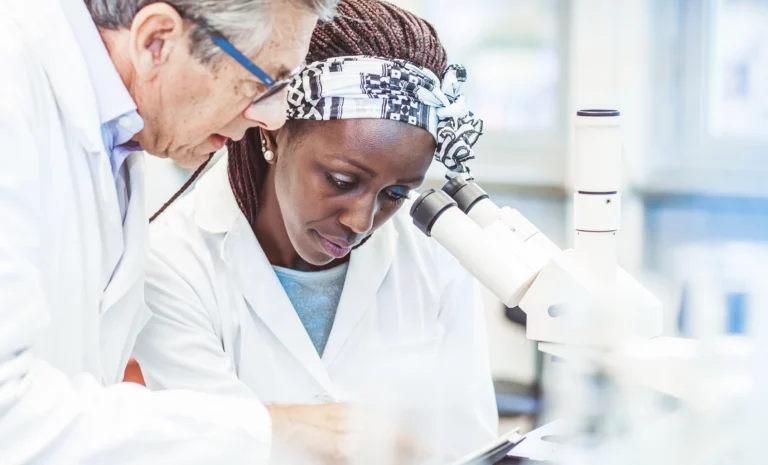 Medical researchers reviewing a skin biopsy sample under a microscope in a laboratory.