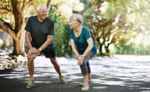 Older couple stretching outdoors before exercise in a sunny park.
