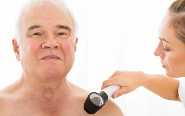 Dermatology provider examining an older man’s shoulder during a second-opinion evaluation for skin cancer treatment.